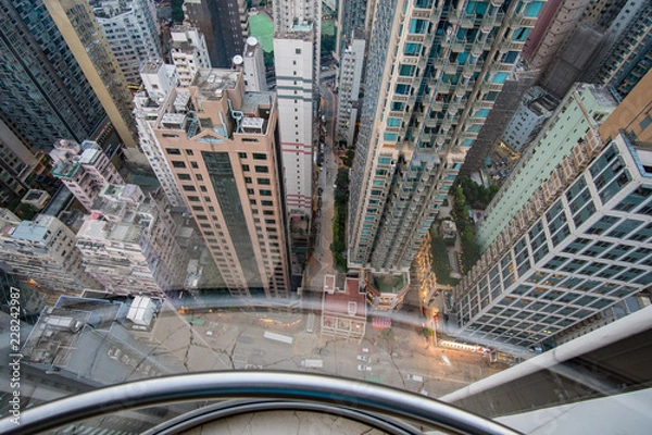 Obraz View from a glass elevator above the city and scyscrapers, vertigo inducing view looking down on a modern city