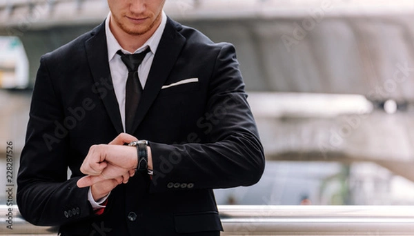 Fototapeta Businessman look at his watch wait for business appointment time.