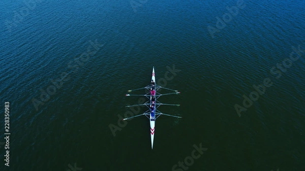 Fototapeta Boat coxed four rowers rowing on the tranquil lake. Aerial view of rowing and rowers.