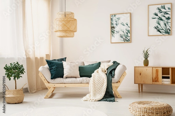 Fototapeta Stylish sofa with grey and green pillows and blankets in the middle of elegant white and bright living room
