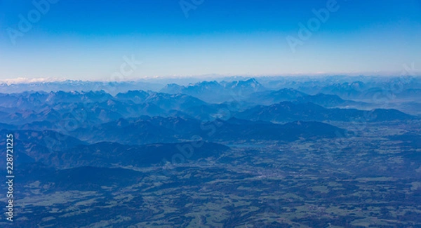 Fototapeta Mountains and blue sky from above. View out of an airplane window.
