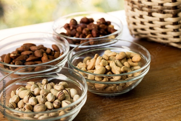 Fototapeta Assortment of mixed nuts and wicker basket on wood table background