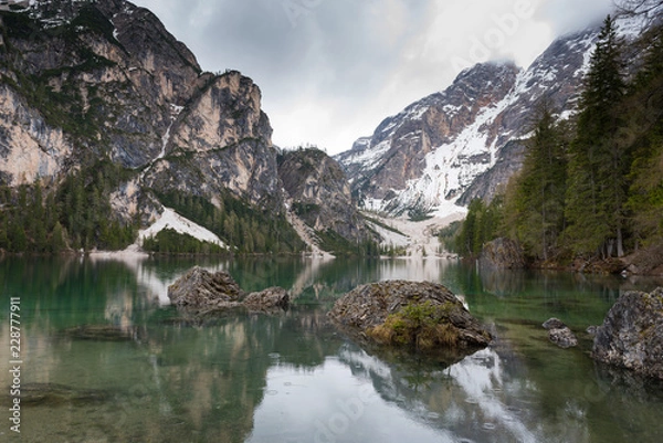 Fototapeta Magnificent lake Lago di Braies. The emerald smooth surface of water reflects the wood and mountains around. Walk to South Tyrol, Italy. The concept of walking and eco-tourism