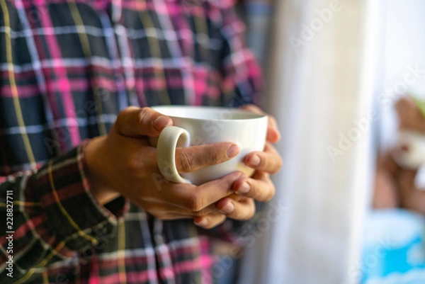 Fototapeta close up hands colding coffee cup in the morning near window f