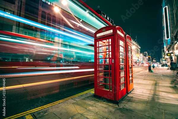 Obraz Light trails of a double decker bus next to the iconic telephone booth in London