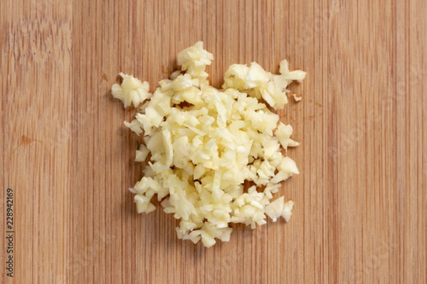 Fototapeta Garlic minced on wooden plate in the middle. Top view