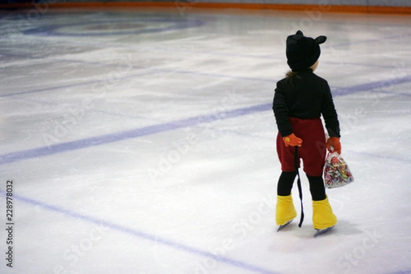 Fototapeta costumed child on ice skates with pack of candy