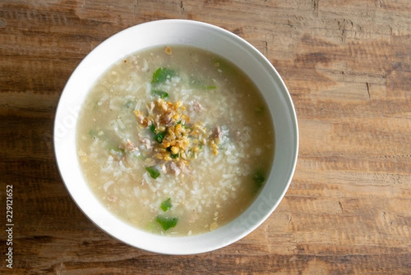 Fototapeta boiled rice in pork soup for a breakfast on wood background and space for text