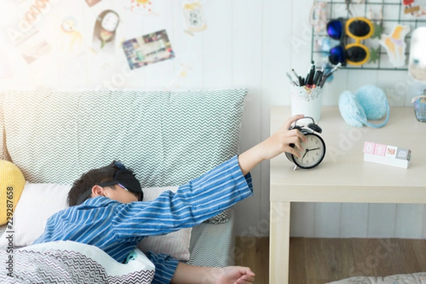 Obraz A kids waking up to an alarm clock in the bedroom