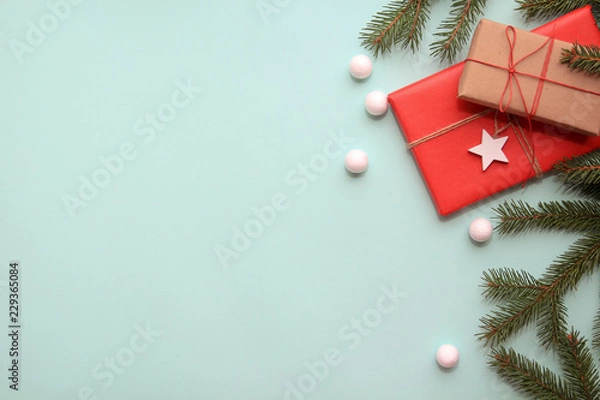 Fototapeta Christmas background. Composition with Christmas gift boxes, fir tree branches and decorations on blue background. Top view with copy space.