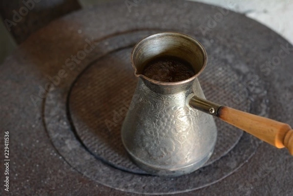 Fototapeta Hot coffee prepared in a Turk. Top view on a beautiful curled foam. Authentic process of preparation of coffee. Coffee brewer. Selective focus