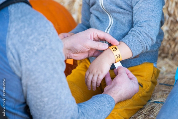 Fototapeta Man putting a paper bracelet on childs hand.
