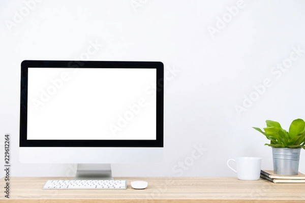 Obraz Modern PC Monitor and white screen, mouse, keyboard and some stuff on the wooden table. White background and copy space. Business or Work space theme