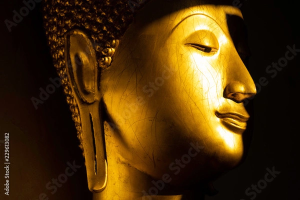Obraz close up face of golden buddha statue in the light and shadow of sun at Wat Pra Sri Mahathat temple, Phitsanulok province, Thailand