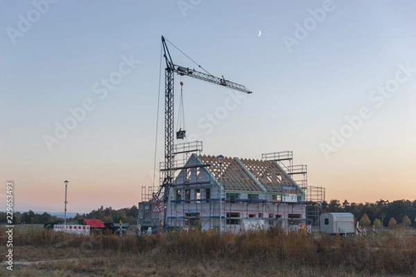 Obraz Eingerüsteter Rohbau mit Kran am Abend