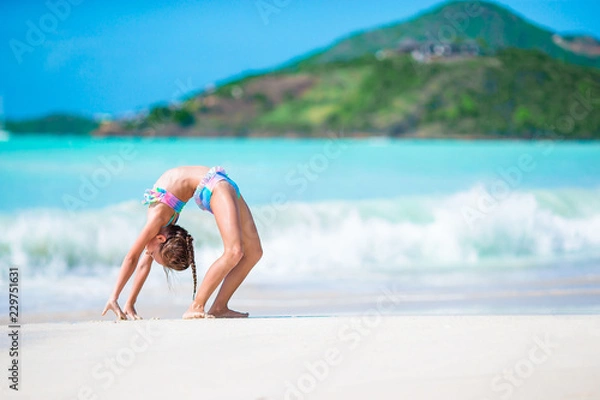 Fototapeta Beautiful little girl on beach having fun. Happy girl enjoy summer vacation background the blue sky and turquoise water in the sea on caribbean island