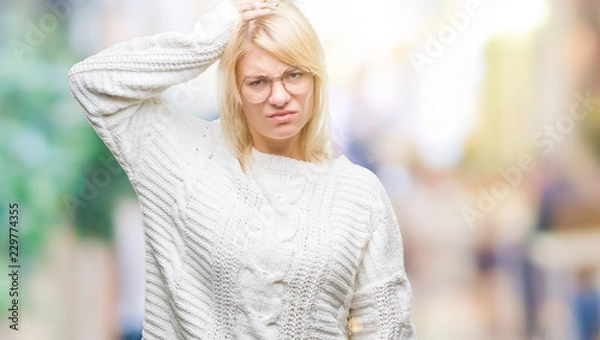 Obraz Young beautiful blonde woman wearing winter sweater and glasses over isolated background confuse and wonder about question. Uncertain with doubt, thinking with hand on head. Pensive concept.