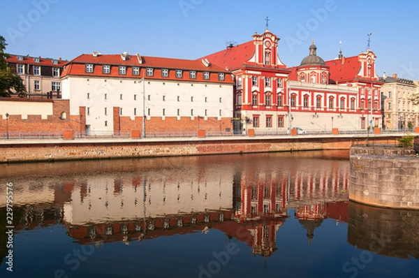Obraz Wroclaw, Poland, August 2018.Ossolineum Library. With reflection in Odra River in the morning sun.