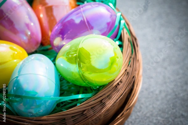 Obraz Multi-colored plastic Easter eggs in a circular brown basket