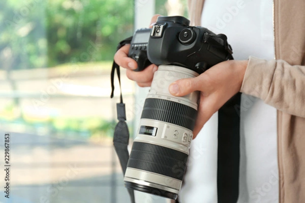 Fototapeta Male photographer with professional camera on blurred background. Space for text