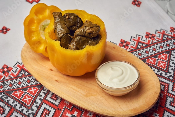 Obraz Traditional romanian or moldavian meal sarmale with meat, rice and vegetables in belle pepper with souce on wooden plate