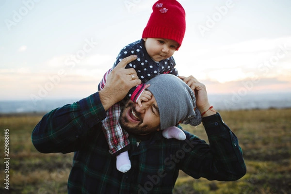Obraz The dad holds his face in his arms. Family photo session at sunset.