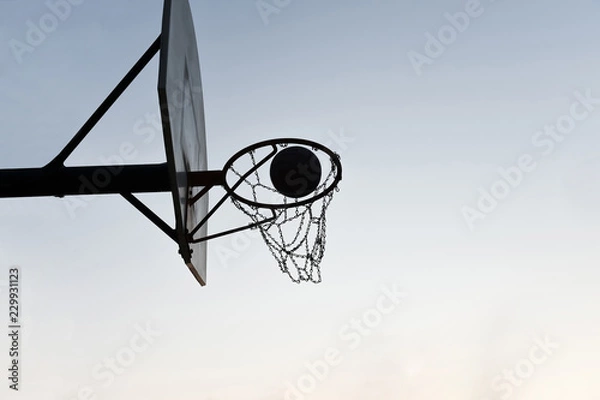 Fototapeta Silhouette of a basketball hoop and backboard at sunset