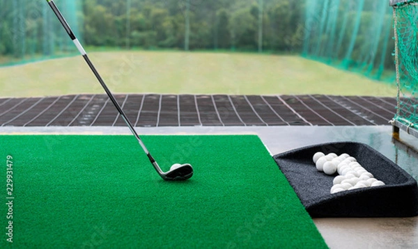 Obraz Golf club and ball on a synthetic grass mat at a practice range.