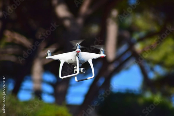Fototapeta Flying drone with a video camera on a blue sky background.
