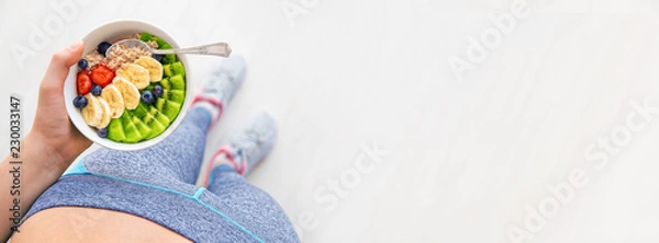 Obraz Młoda kobieta odpoczywa i je zdrowego owsiankę po treningu.