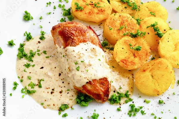 Fototapeta chicken breast under sour cream mustard sauce garnished with potato and sprinkled with parsley