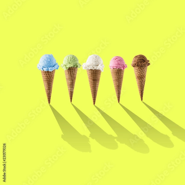 Fototapeta Variety of ice cream flavor in cones blueberry ,strawberry, green tea, chocolate and coconut setup on yellow background . Summer and Sweet menu concept.