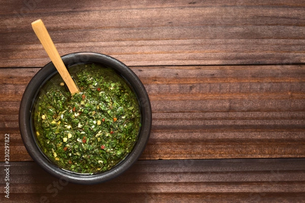 Fototapeta Surowe domowe argentyńskie zielone salsa chimichurri lub sos wykonany z pietruszki, czosnku, oregano, gorącej pieprzu, oliwy z oliwek, octu, sfotografowanego napowietrznego z naturalnym światłem (selektywne skupienie się na salwie)