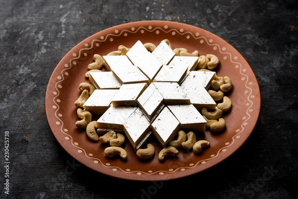 Fototapeta Kaju Katli is a Diamond shape Indian sweet made using cashew sugar and mava, served in a plate or bowl over moody background. selective focus