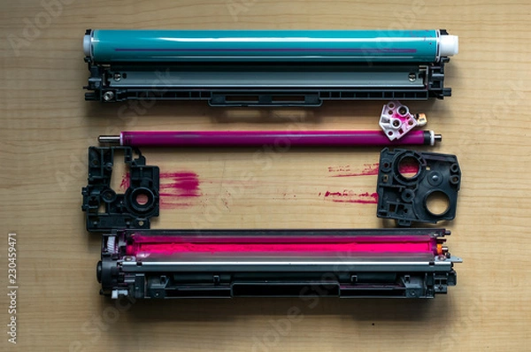 Fototapeta Disassembled into parts of the color cartridge from the laser printer is on a wooden table