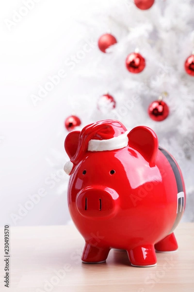 Fototapeta Piggy bank in front of a white Christmas tree