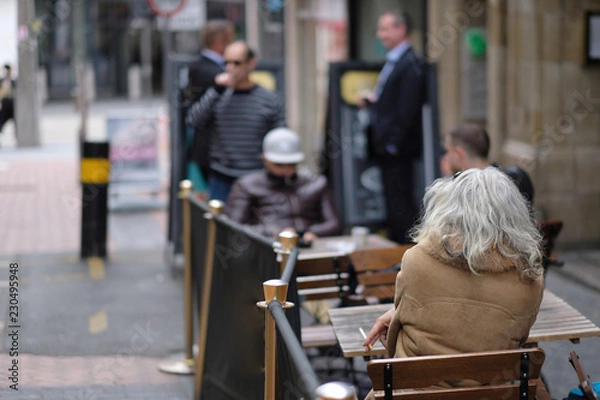 Obraz People sit at the tables of a street cafe in a European city in spring