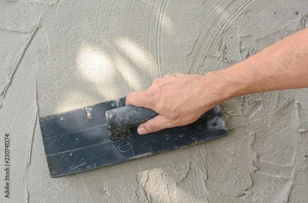 Obraz Hand on be bound with cement , do cement work, apply cement (over a surface)
