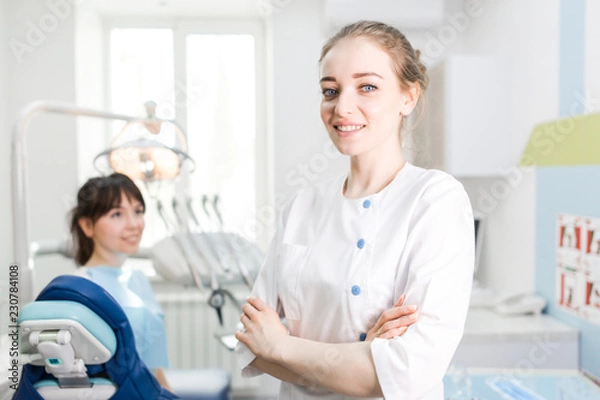 Fototapeta Portrait of a beautiful dentist girl in the clinic on the background of the patient
