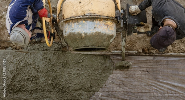 Fototapeta Workers pour concrete solution at a construction site