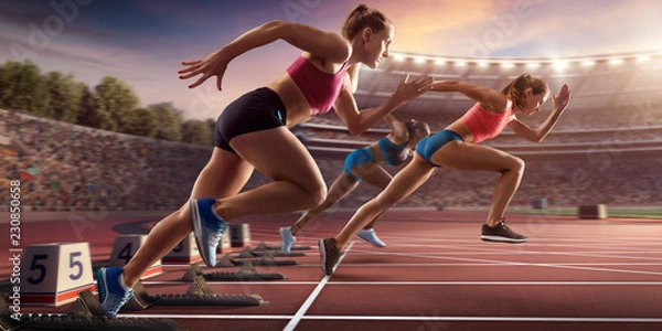 Obraz Female athletes sprinting. Three women in sport clothes run at the running track in professional stadium