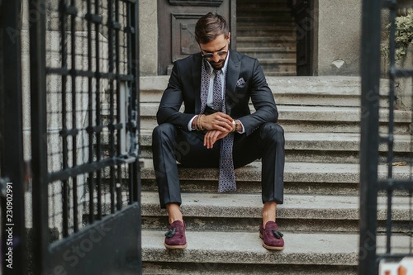 Fototapeta Businessman waiting on the stairs and looking at the time