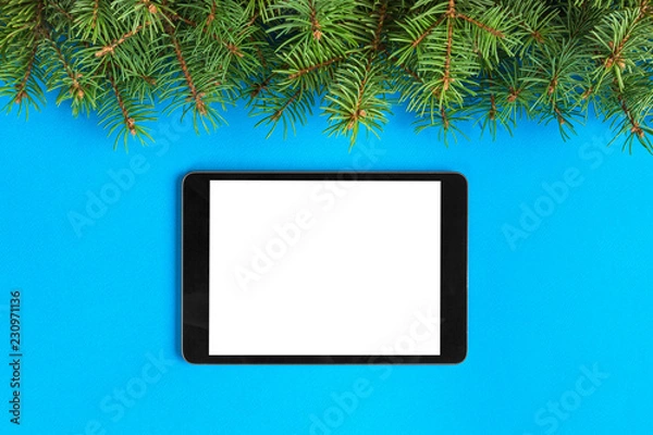 Fototapeta Tablet with blank screen on the blue pastel color background. Top view with christmas decor