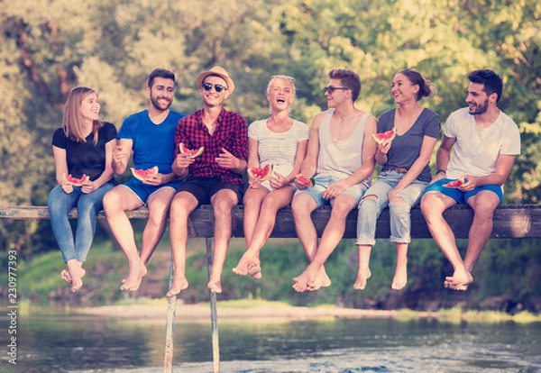 Fototapeta znajomych korzystających z arbuza siedząc na drewnianym moście