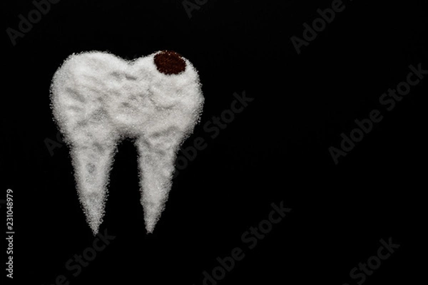 Fototapeta tooth made of sugar on a black background with caries