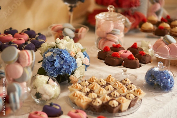 Fototapeta Wedding candy bar service. Delicious macaroons, cookies, pieces of cake and other sweets with chocolate, berries and cream served on the dinner table
