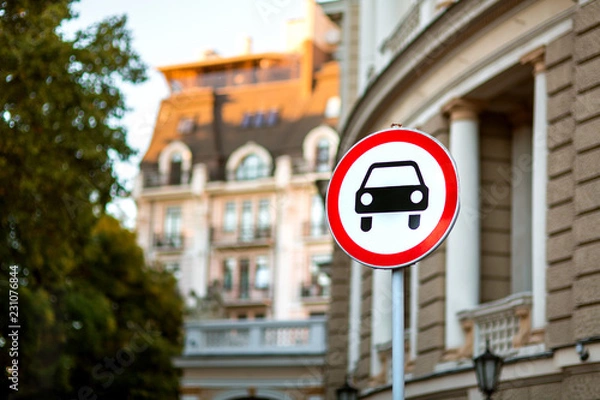 Fototapeta A car sign prohibiting the passage of passenger cars, a round sign with a red border on a white background is installed near an architectural building in a European city.
