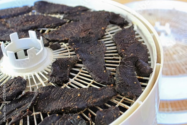 Fototapeta Closeup of dried spiced deer jerky slices on a dehydrator