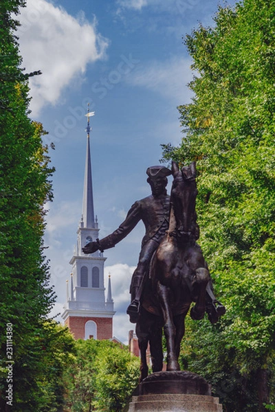 Fototapeta Statue of Paul Revere and spire of Old North Church between trees, in North End, Boston, USA