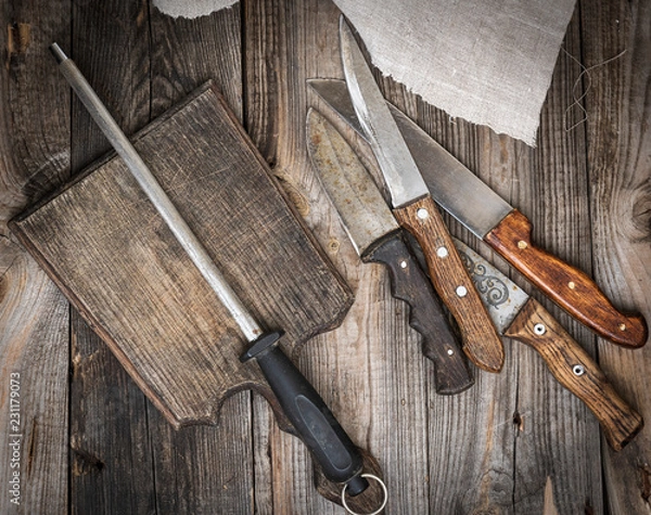 Obraz  old brown wooden cutting board and knife with sharpening on the table